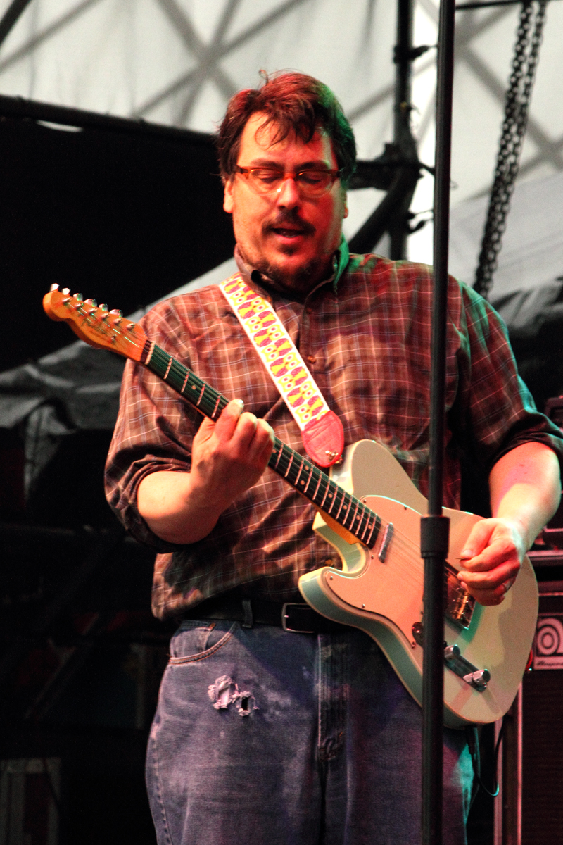 a man with glasses playing an electric guitar