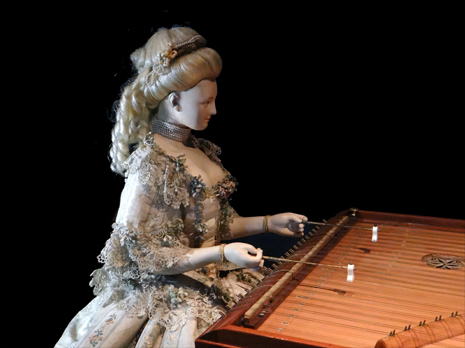 a sculpture sits holding a wooden musical instrument