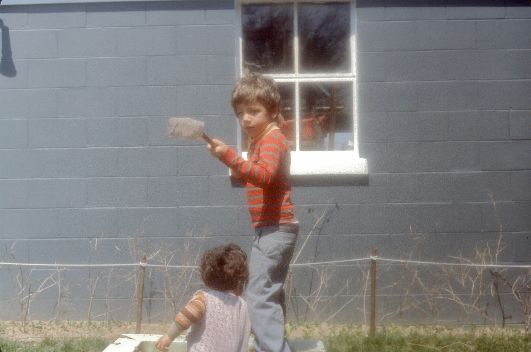 the little boy and the little girl are playing outside the window