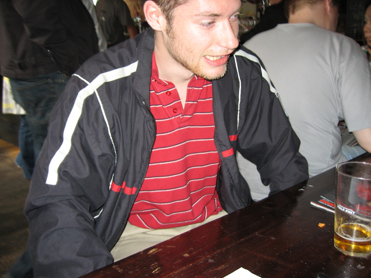 man looking down while sitting at bar with beer