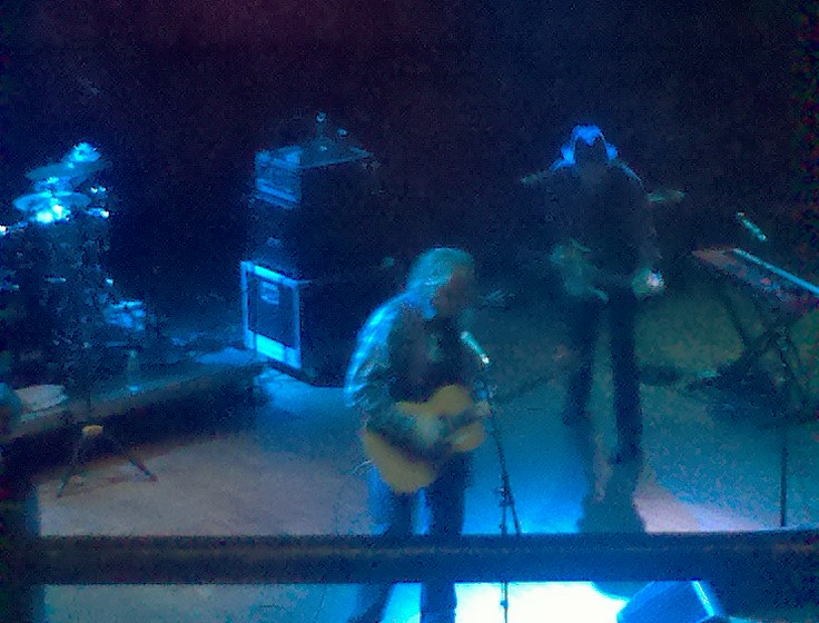 two men singing in front of microphones while playing guitars