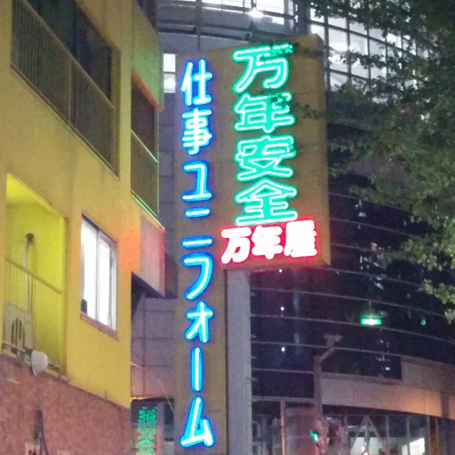 a neon sign at the bottom of a building in tokyo