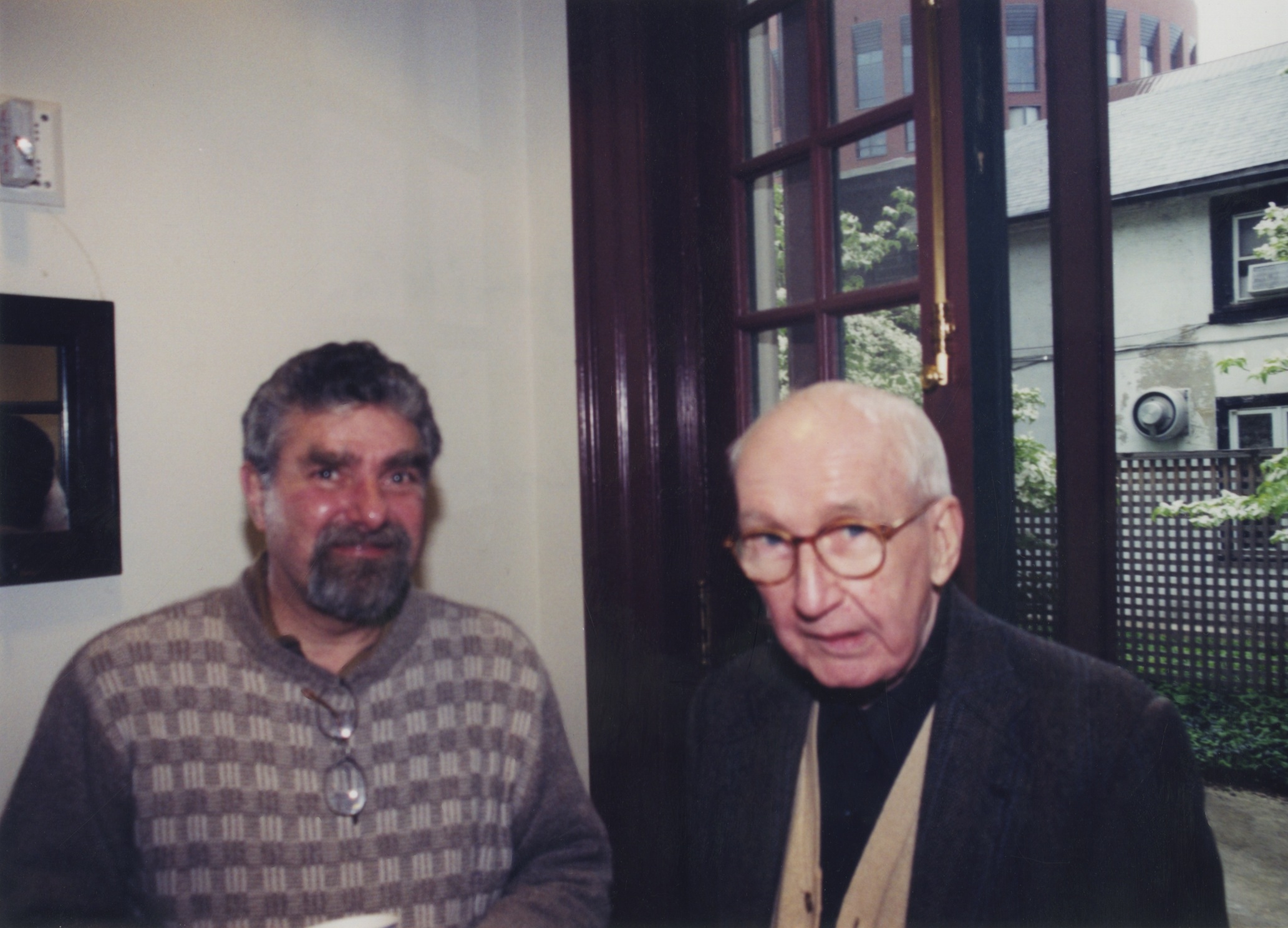 there are two men, one in glasses and one looking into the camera