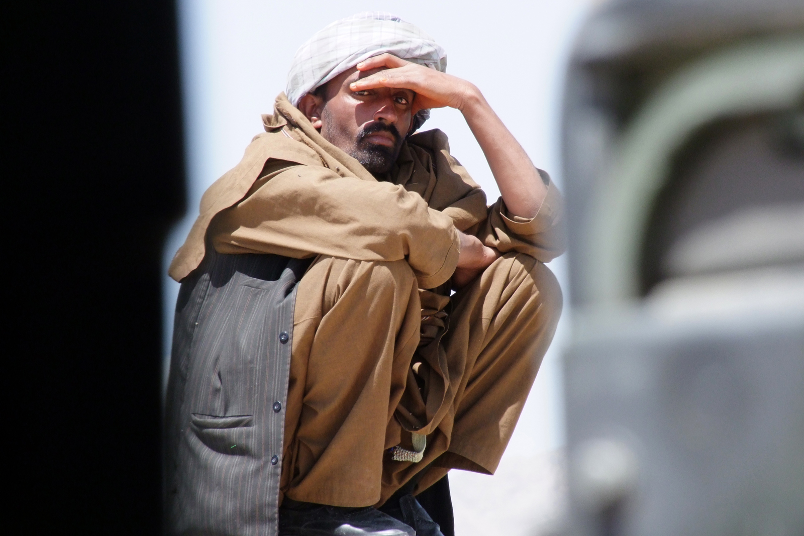 an older man holds his head against his coat