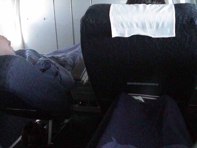 an airplane that is very empty with two people sleeping