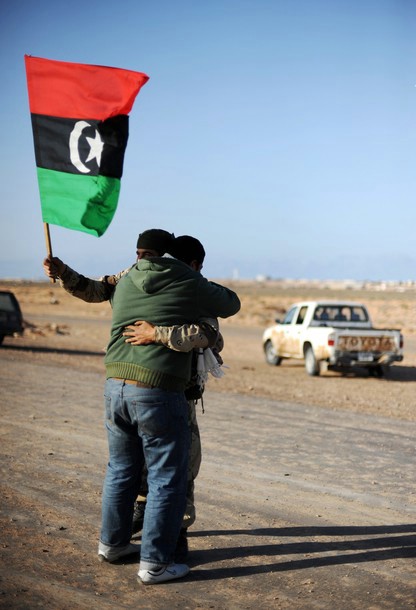 two men are hugging each other in the dirt while holding a flag