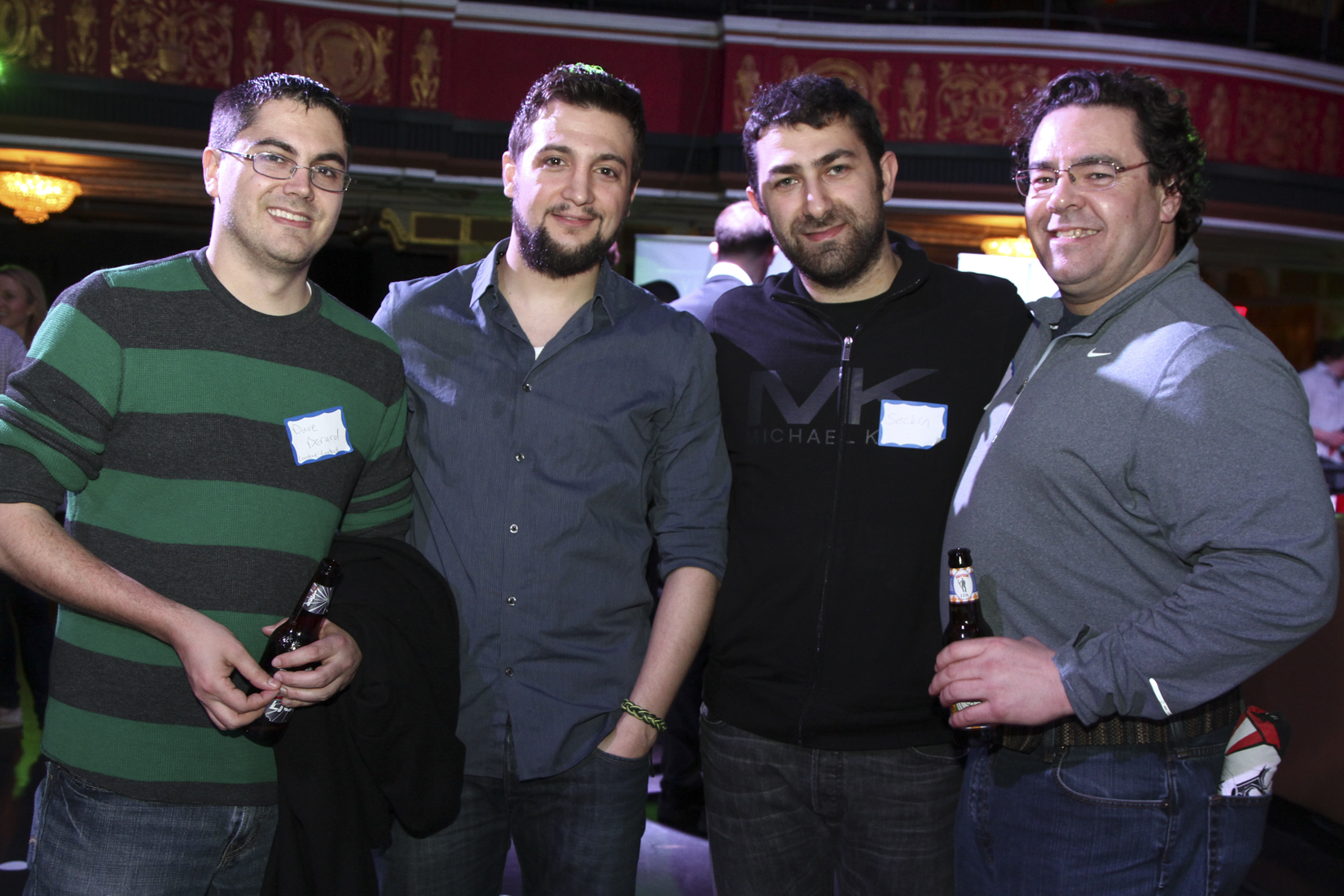 a group of men smiling with drinks in each hand