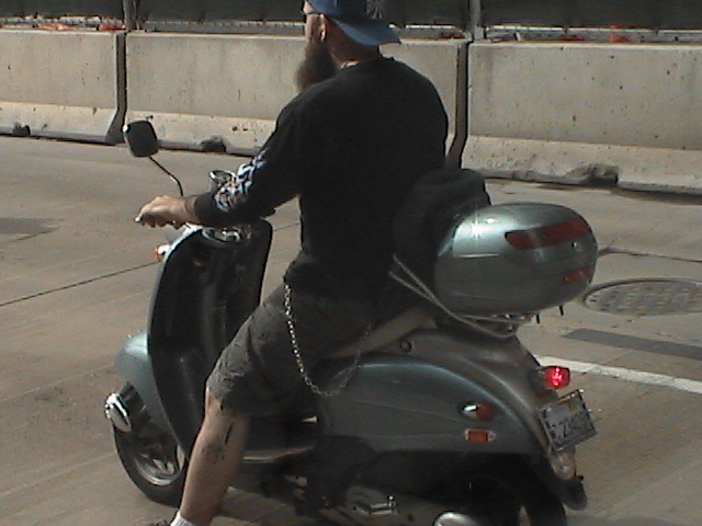 a person on a scooter with a helmet on and talking on the phone