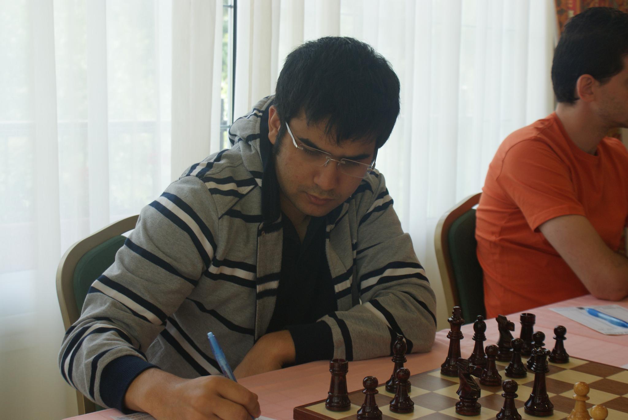 a man playing chess next to another person