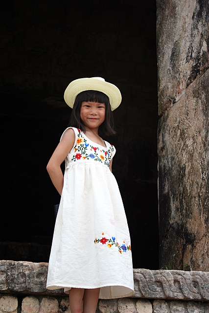 a little girl wearing a white dress and hat