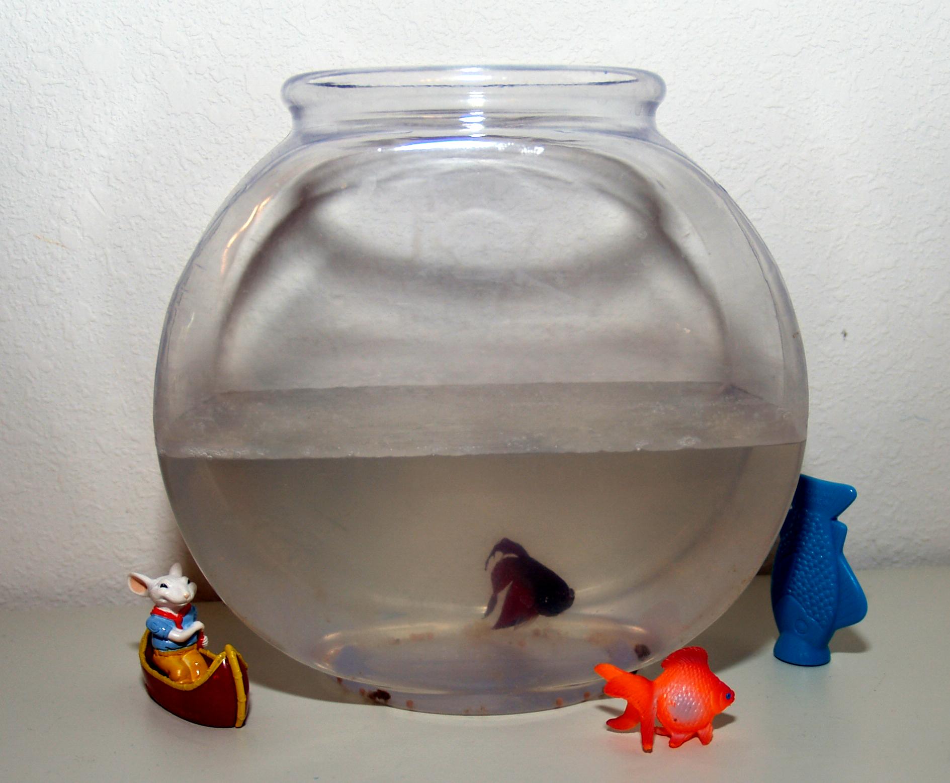 a fish bowl and plastic toy on a table