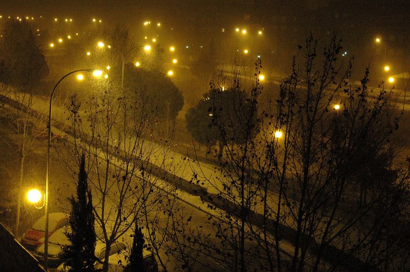 the snowy streetlightes shine in a city at night