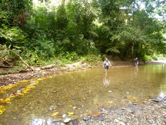 two people stand on a bank with rocks in the water