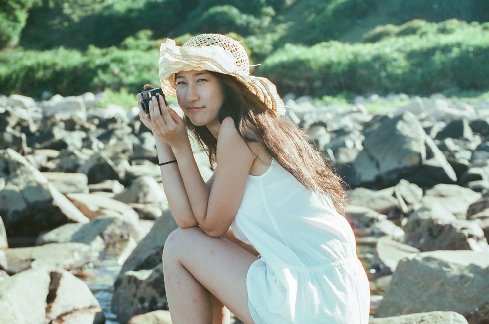 a woman with a hat sitting on rocks taking a po