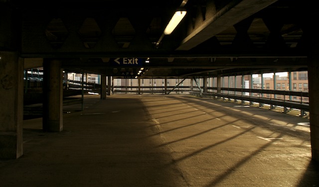a large covered train track by a parking garage