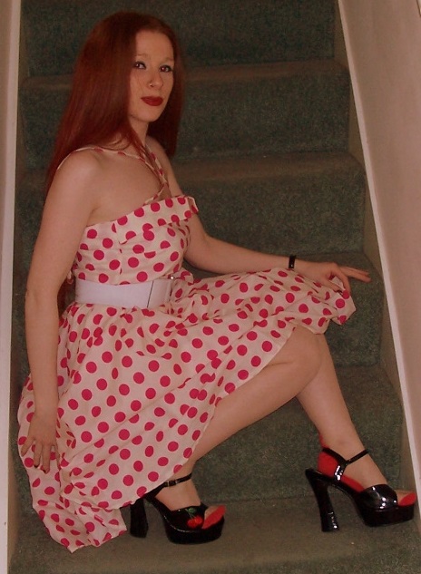 a woman sitting on top of a set of stairs wearing a polka dot dress