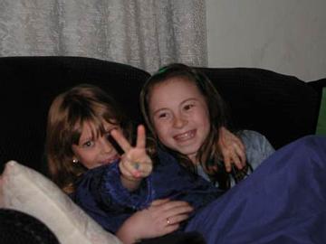 two little girls sitting on a couch with one showing the peace sign