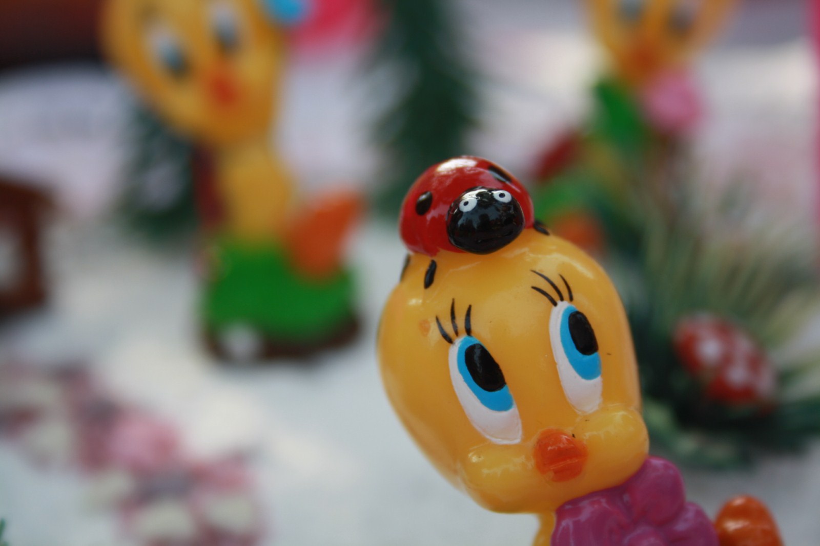 a close up of a toy bird with a lady bug on its head