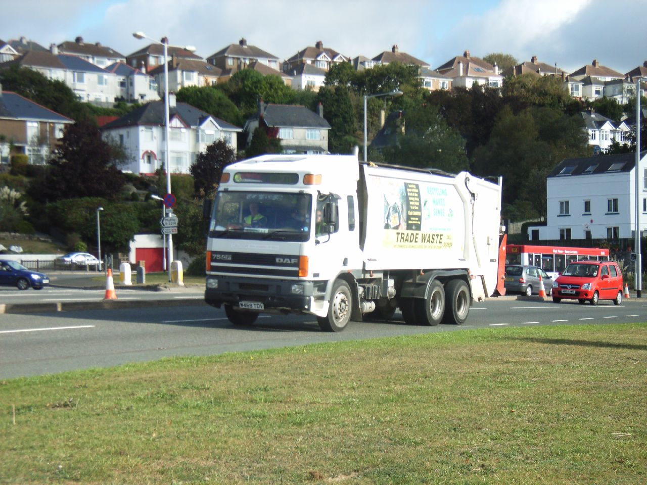 a white truck driving down the street with several houses in the background