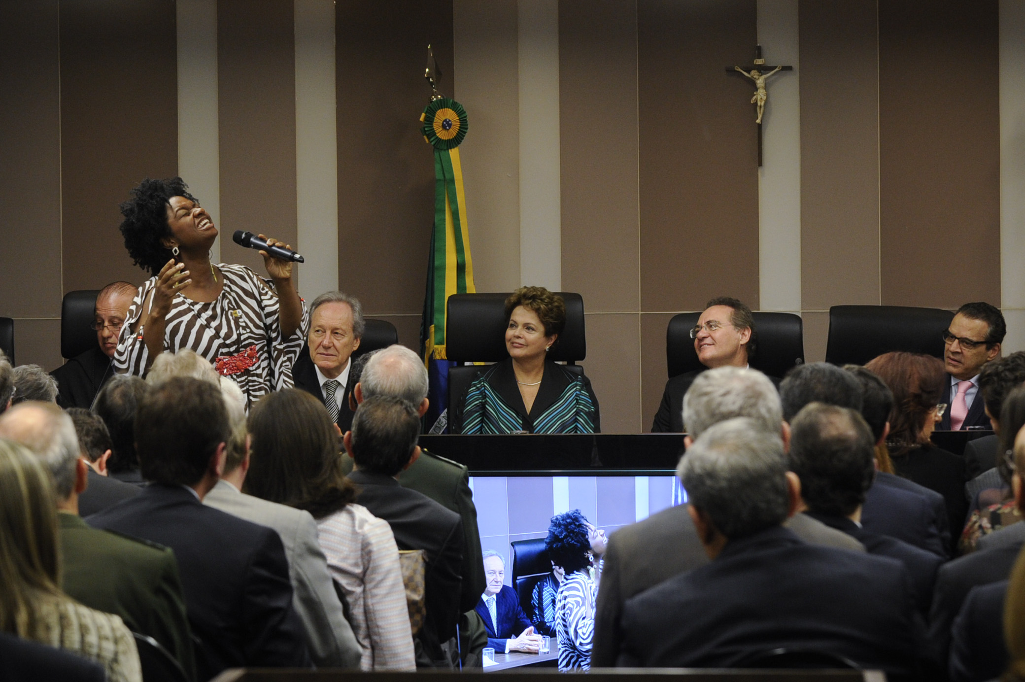 a man talking to two women at a microphone in front of people