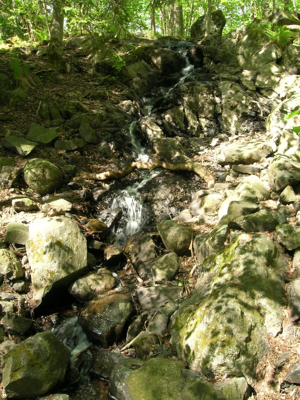 a waterfall cascades from a hill in the woods