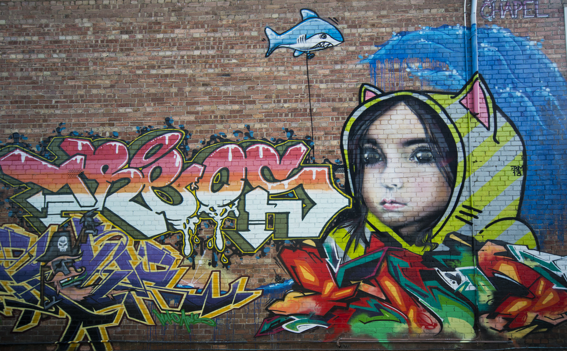 graffiti is on a building, a girl wearing a yellow hoodie