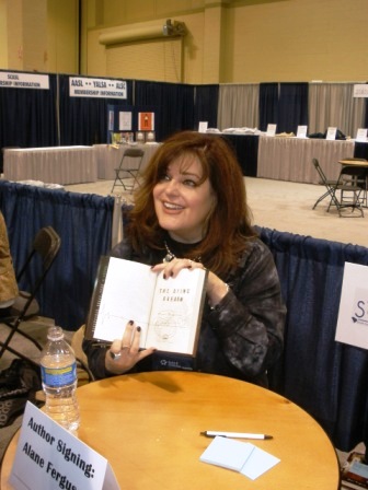a woman holding an open book in front of a table with people sitting on it
