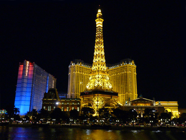 the eiffel tower lit up brightly next to vegas in las vegas