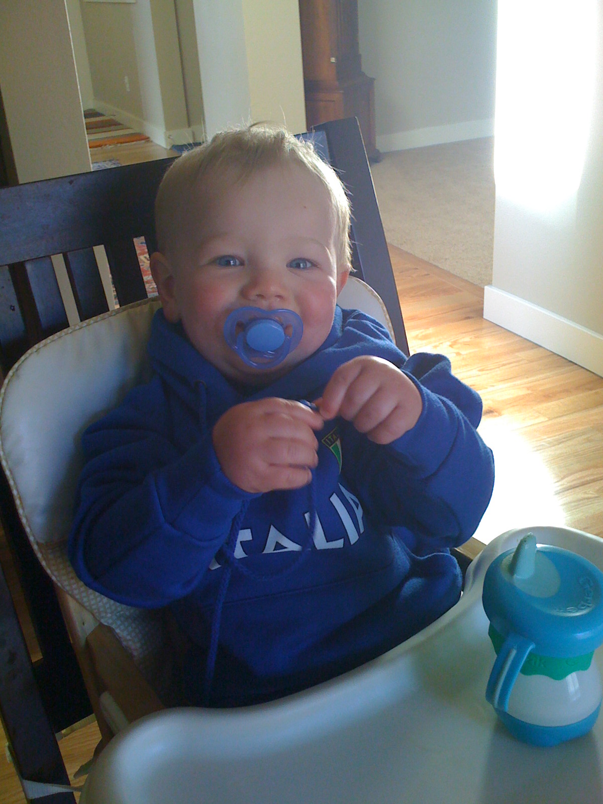 a baby wearing a blue hooded jacket with a pacifier