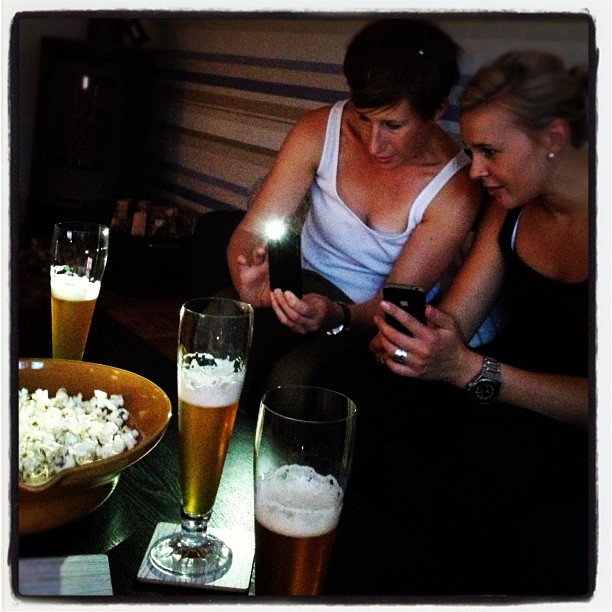 two ladies on their cell phones next to beers