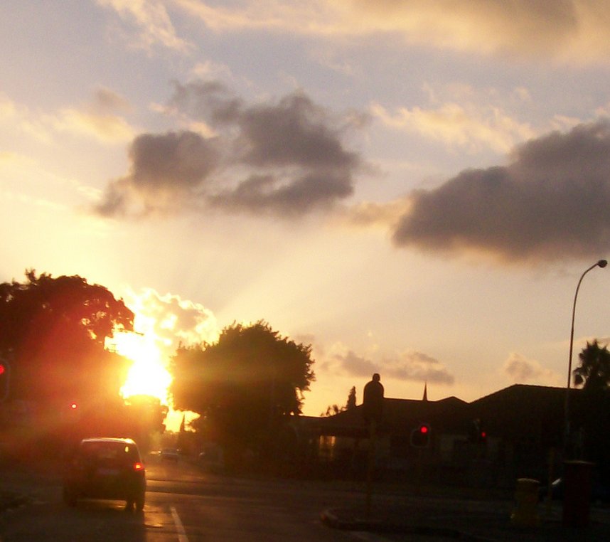 the sun is setting as cars pass in front of a town