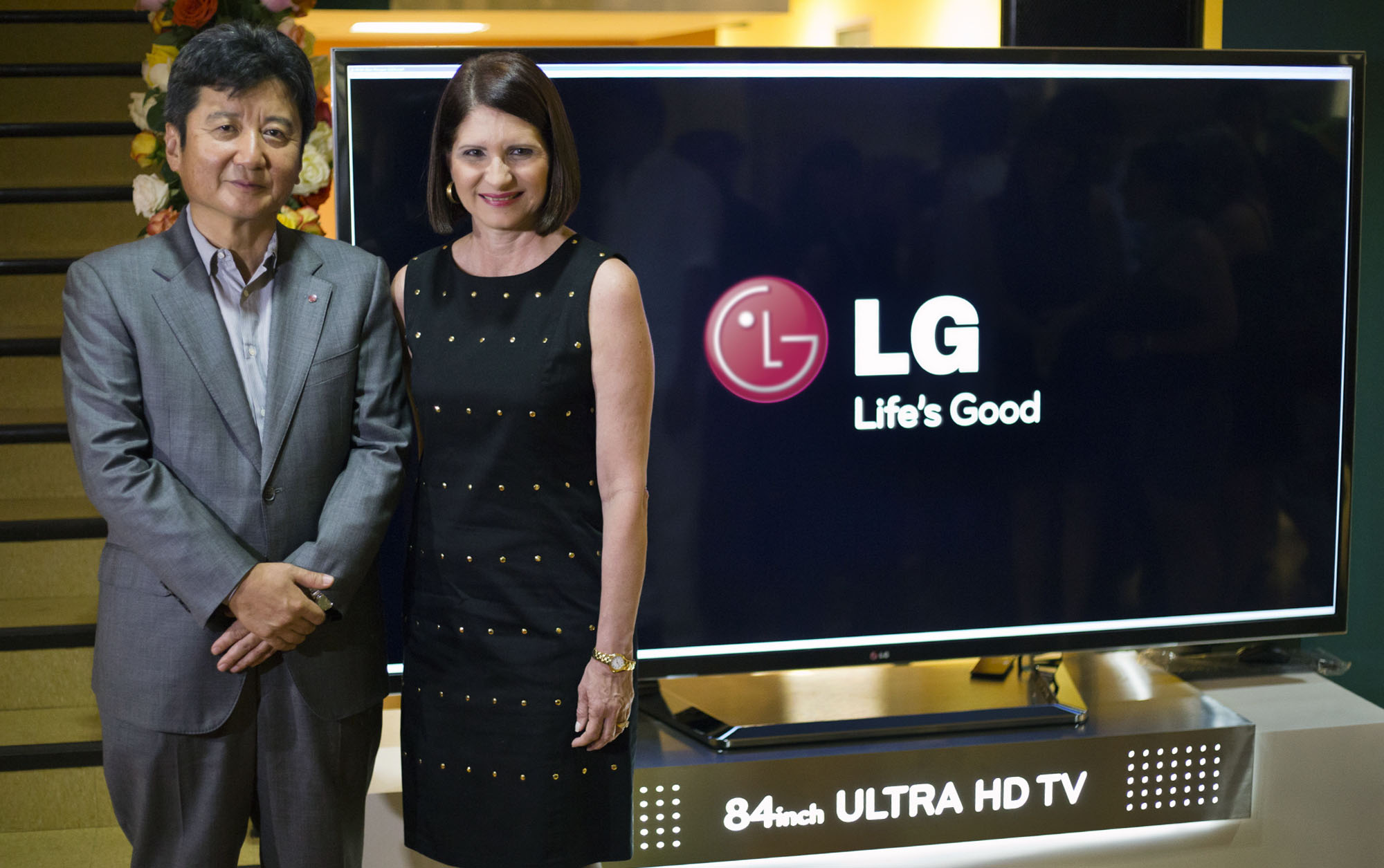 a man and a woman posing in front of a television screen