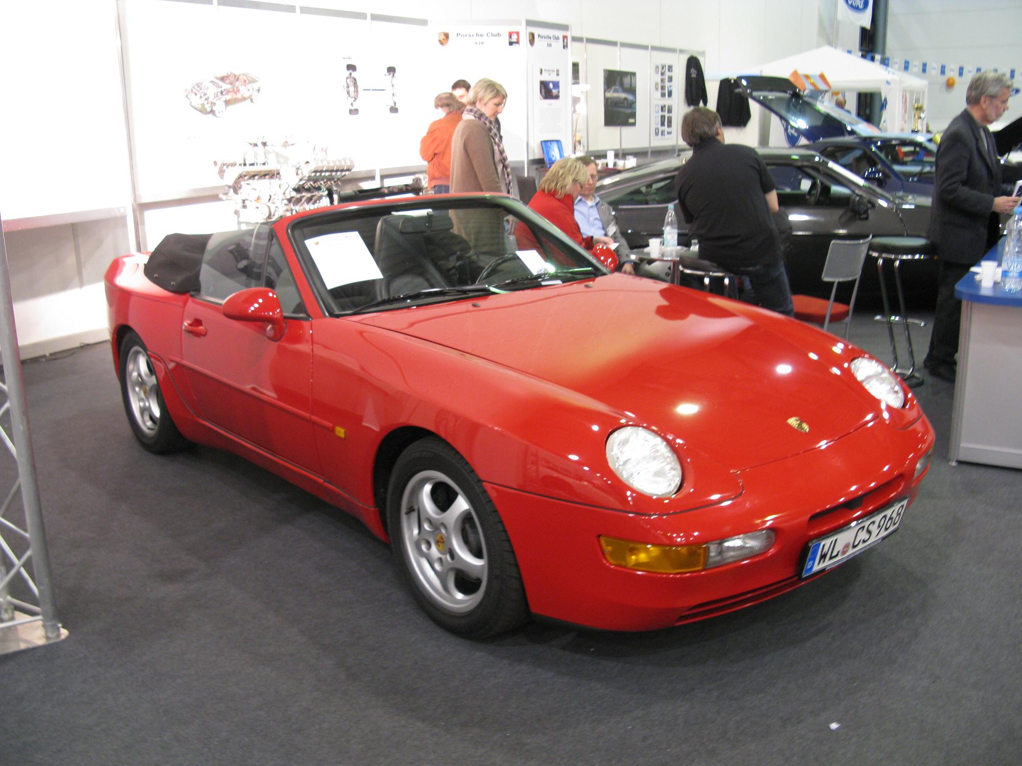 people and a red sports car at an automobile show