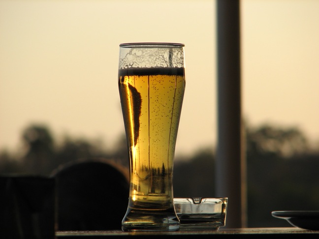 a glass of beer is seen in front of the backdrop
