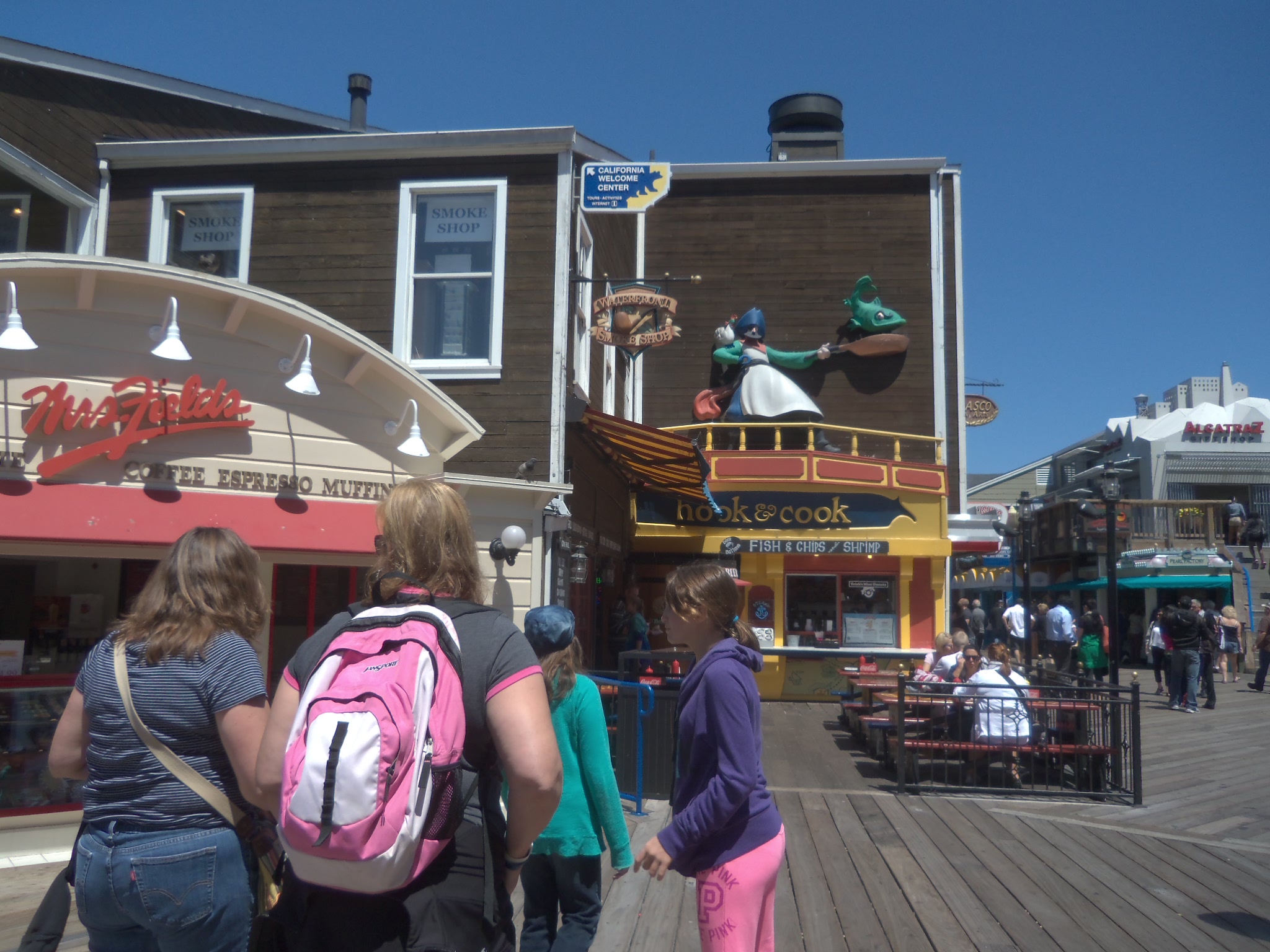 a group of people walking past buildings at a boardwalk