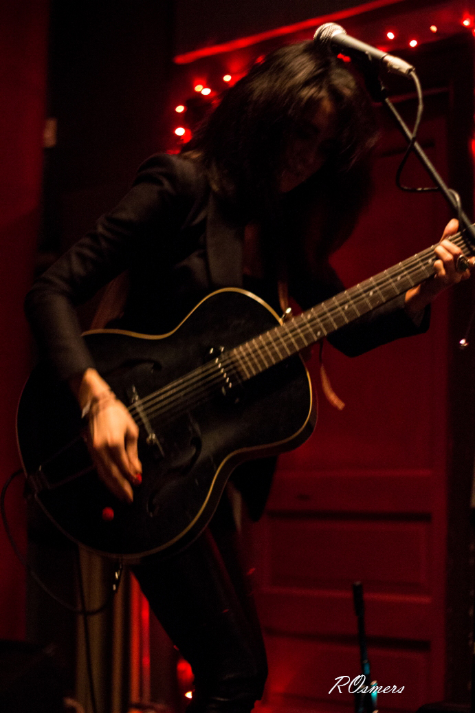 a woman is playing an acoustic guitar in front of a microphone