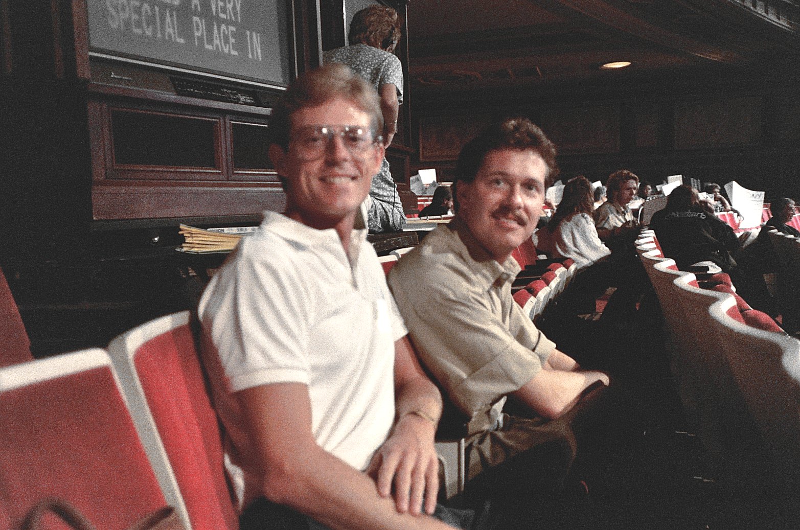 two men are sitting side by side in an auditorium