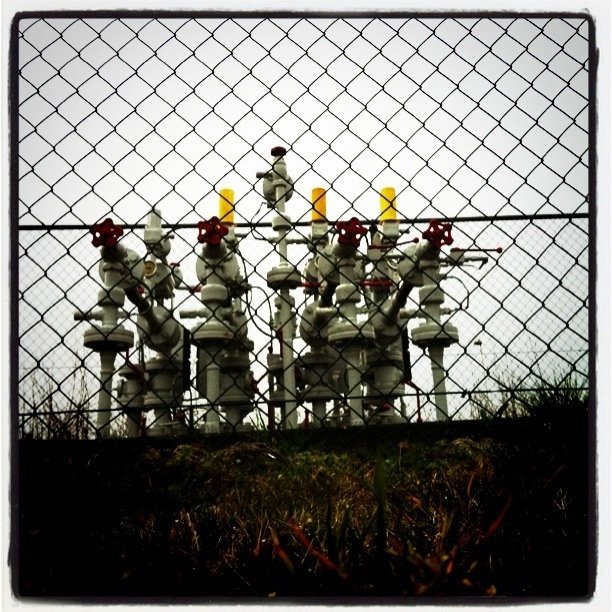an array of white pipes behind a barbed wire fence