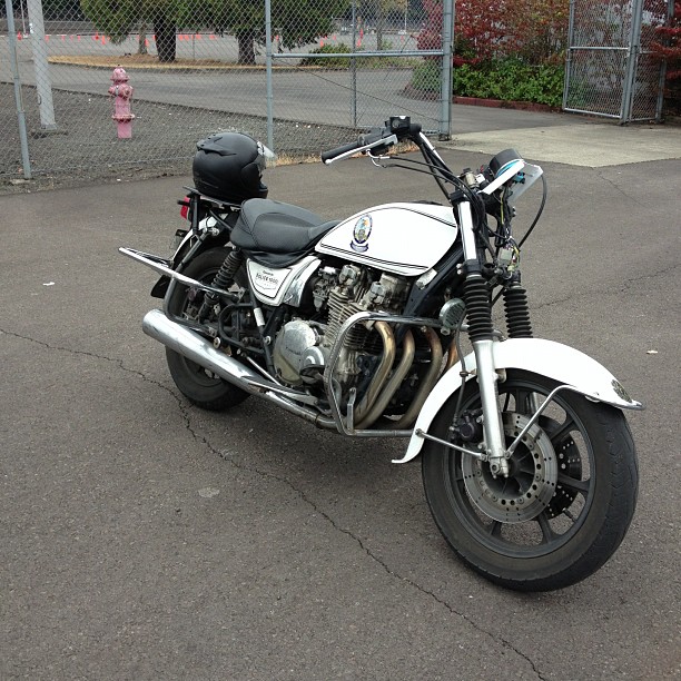 motorcycle parked in a parking lot, close to chain link fence
