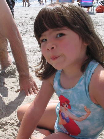little girl in blue on a beach with the sand