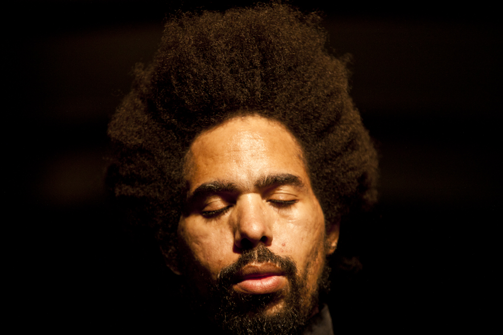 an african american man with curly hair looks intently at the camera