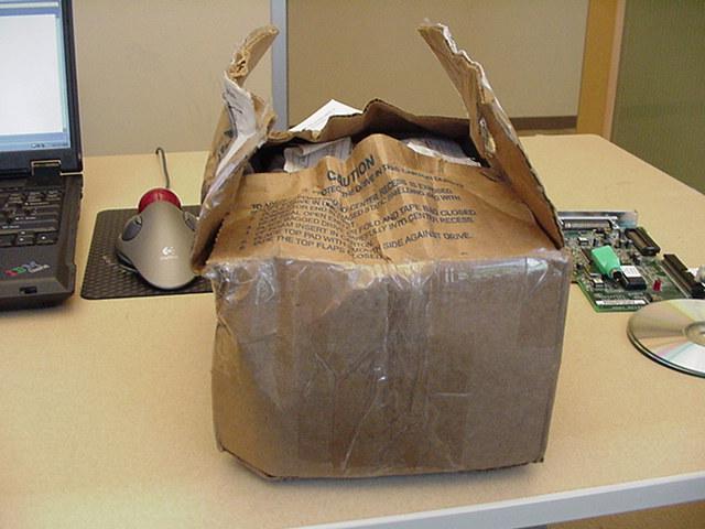 a brown bag with a note on it sitting by a laptop