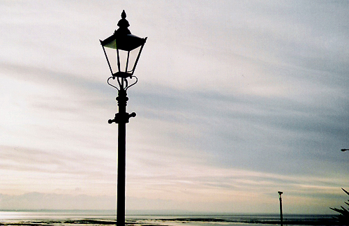 an old street light with an ocean view in the background