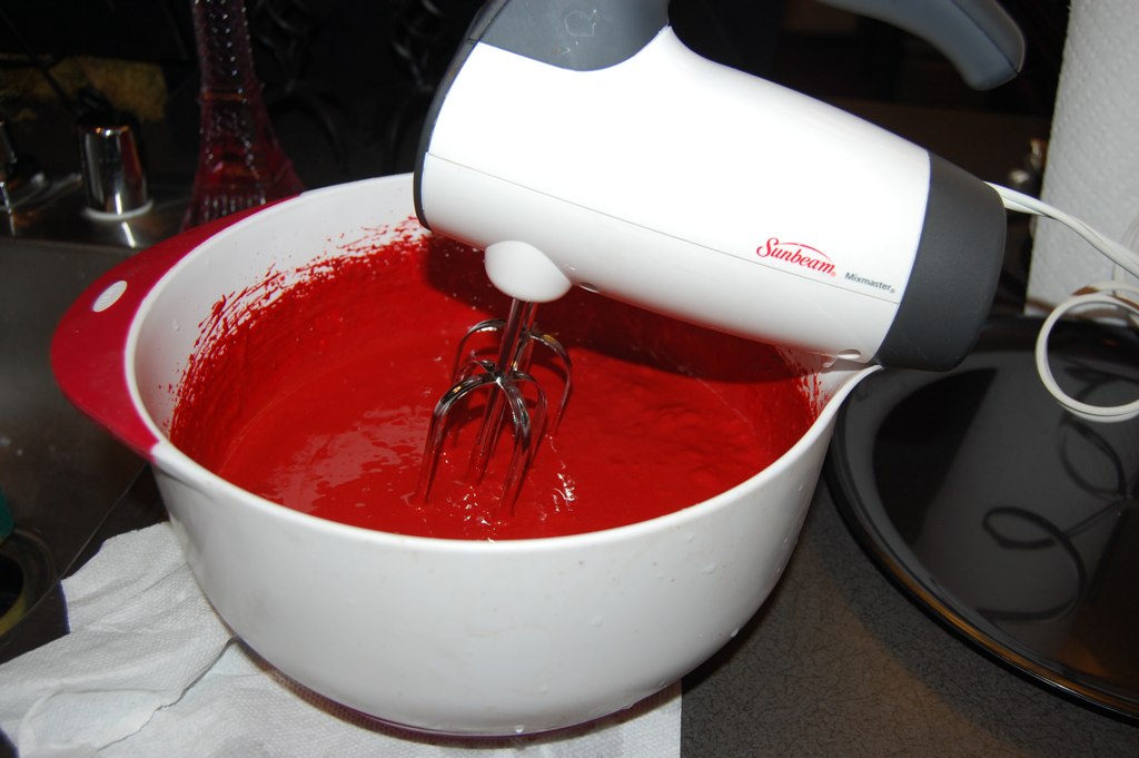 a mixer mixing a red substance on top of a counter