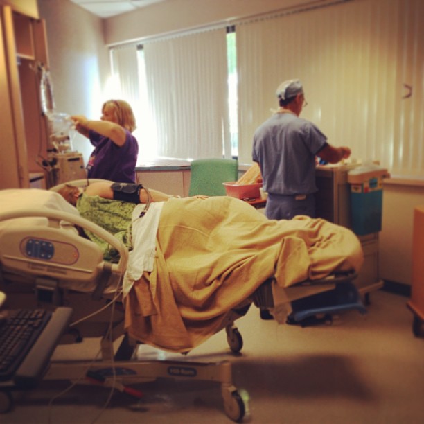 a couple of people standing around a hospital bed