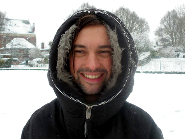 a smiling young man in the snow outside
