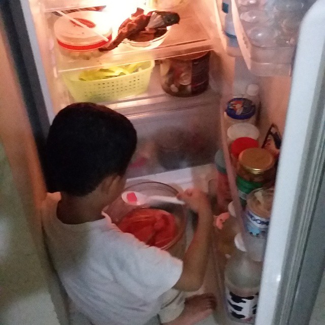a young man is taking his food out of the refrigerator