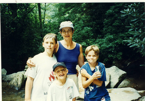 a lady standing with two boys in front of rocks