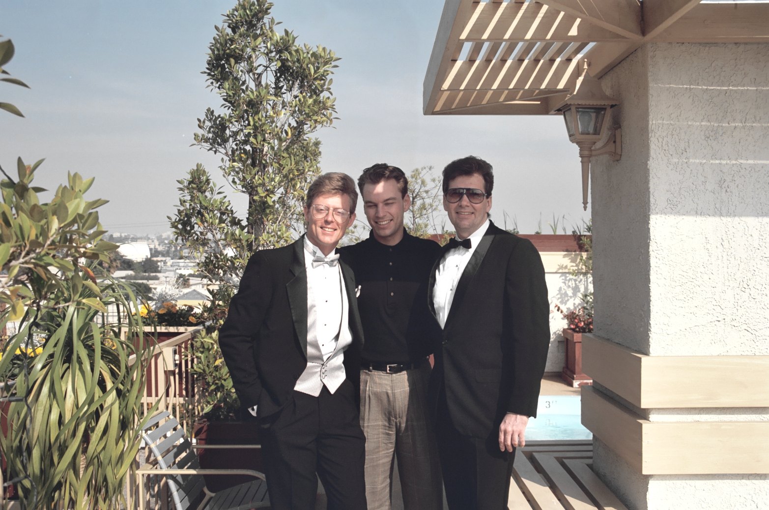 three men in formal attire standing outside near a building