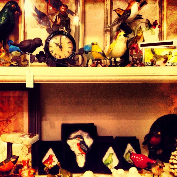 a shelf is full of glass figurines, clock and other decorations